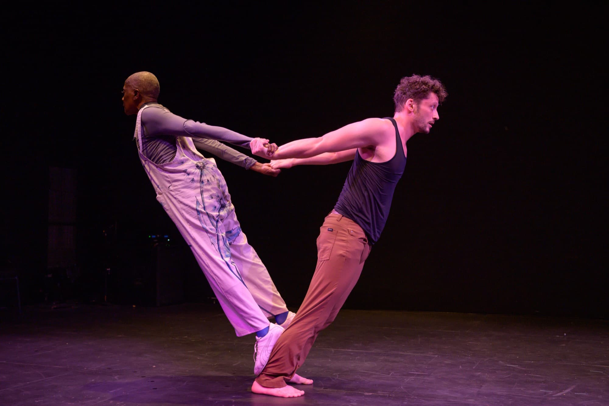 Rhonda and Ben lean back from each other, hands joined, on stage.